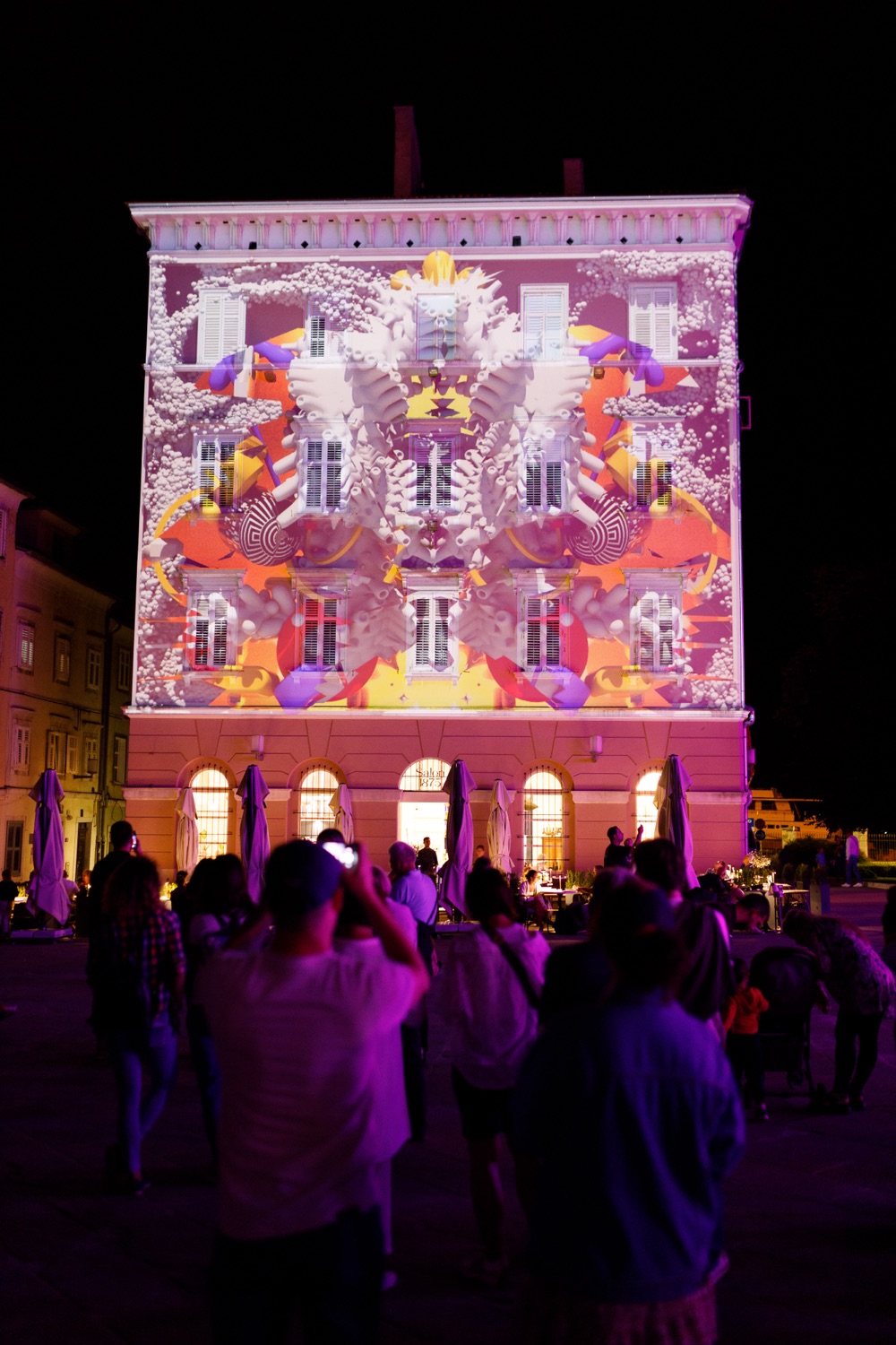 Mapping u toplim bojama preko cijelog pročelja, publika u ljubičastom svjetlu