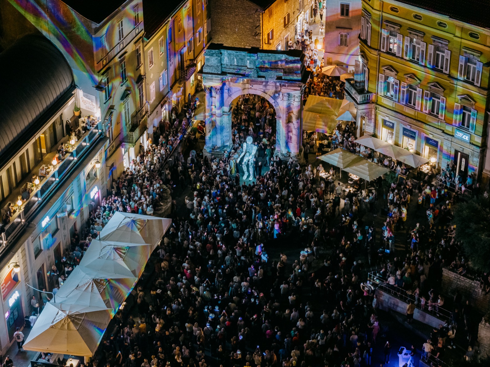 Zračni kadar slavoluka, bijele figure i publike pod suncobranima